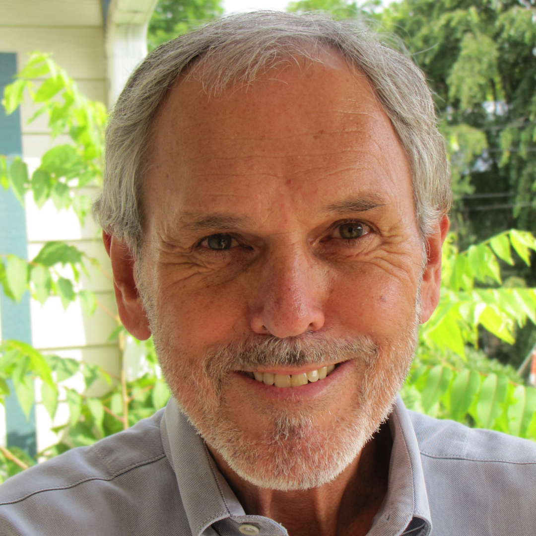 A white man with short, gray hair wearing a collared shirt.