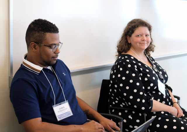 Chris Robinson (left) and Jennifer Smith (right) seated in front of a white board.