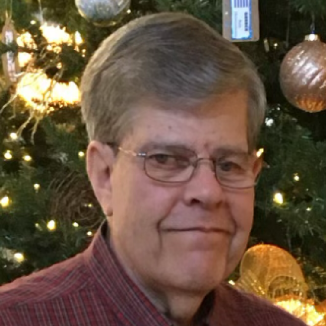 A white man with short, gray hair and wire glasses.